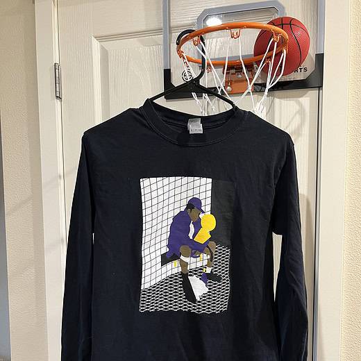Front view of a black Gildan long-sleeve tee with Kobe Bryant holding the NBA Championship trophy illustration, Adult Small.