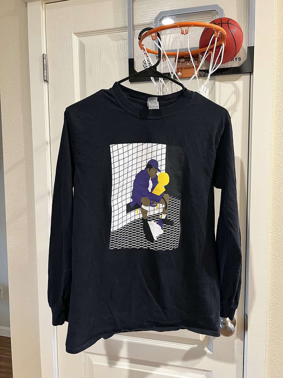 Front view of a black Gildan long-sleeve tee with Kobe Bryant holding the NBA Championship trophy illustration, Adult Small.