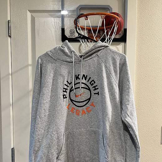 Front view of a gray Nike hoodie with "Phil Knight Legacy" design, including a front kangaroo pocket.
