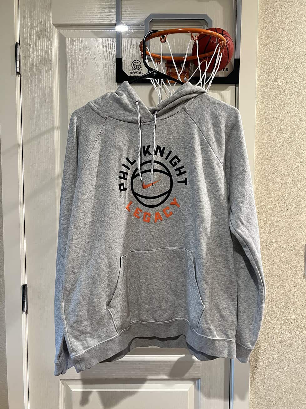 Front view of a gray Nike hoodie with "Phil Knight Legacy" design, including a front kangaroo pocket.