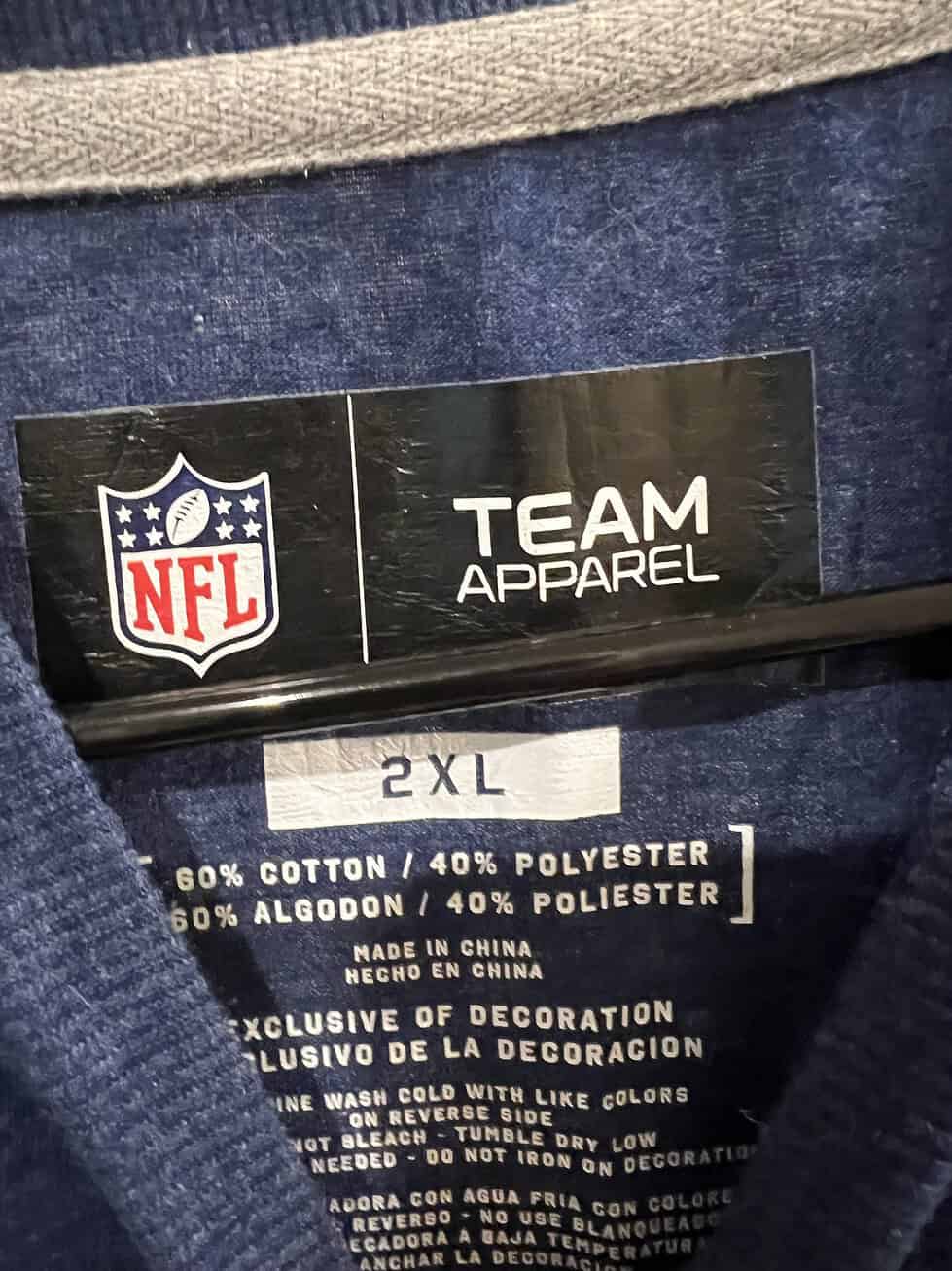 Close-up of the NFL Team Apparel size tag on a blue Patriots T-shirt, labeled 2XL.