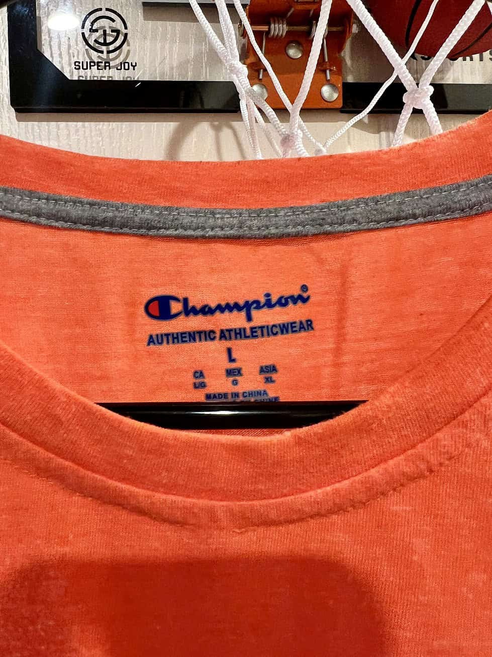 Close-up of Champion logo on the inside collar of an orange Oregon State Beavers T-shirt, Adult Large.