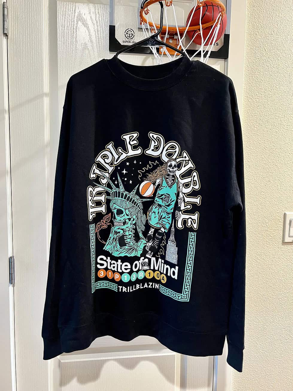 Front view of the "Triple Double" design celebrating Sabrina Ionescu and the 2024 WNBA Champions, featuring NYC-inspired elements on a black Trillblazin sweatshirt.