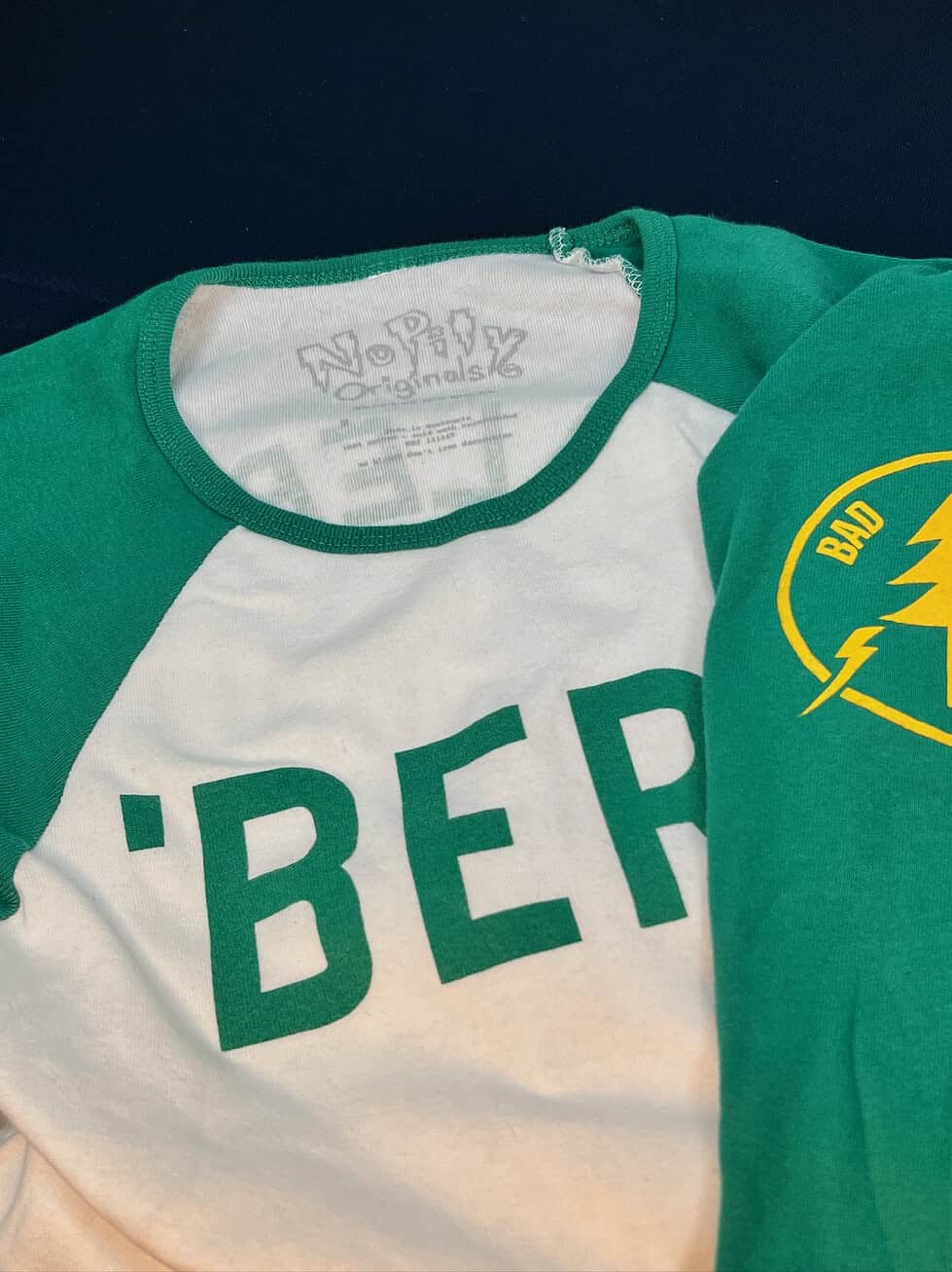 Close-up of front neckline and sleeve logo on baseball tee