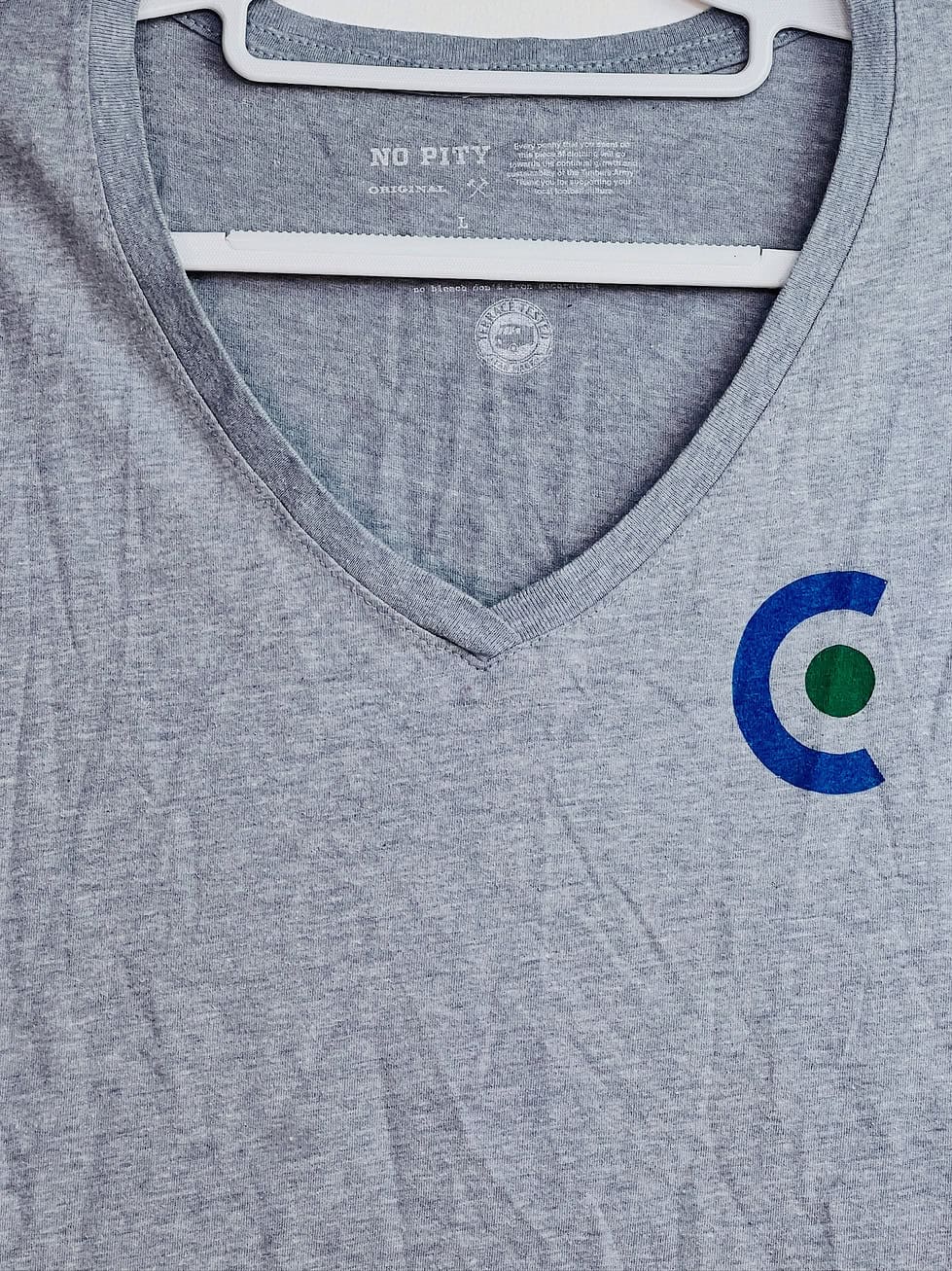 Close-up of Cascadia ‘C’ emblem on gray v-neck tee
