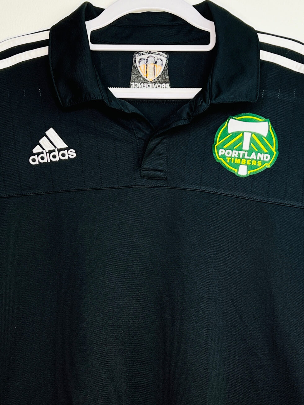 Close-up of Timbers crest on black Adidas polo