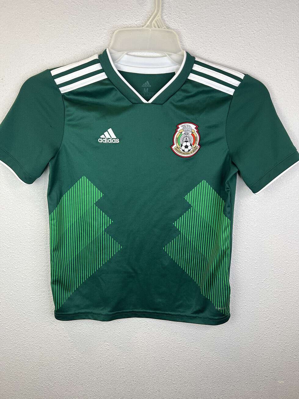 Front view of green Adidas Youth Mexico soccer jersey, size Medium, featuring Mexico crest and zigzag graphics.
