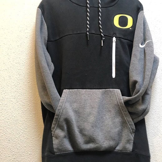 Front view of black and gray two-tone Nike Oregon Ducks hoodie with yellow “O” logo and chest zipper pocket.