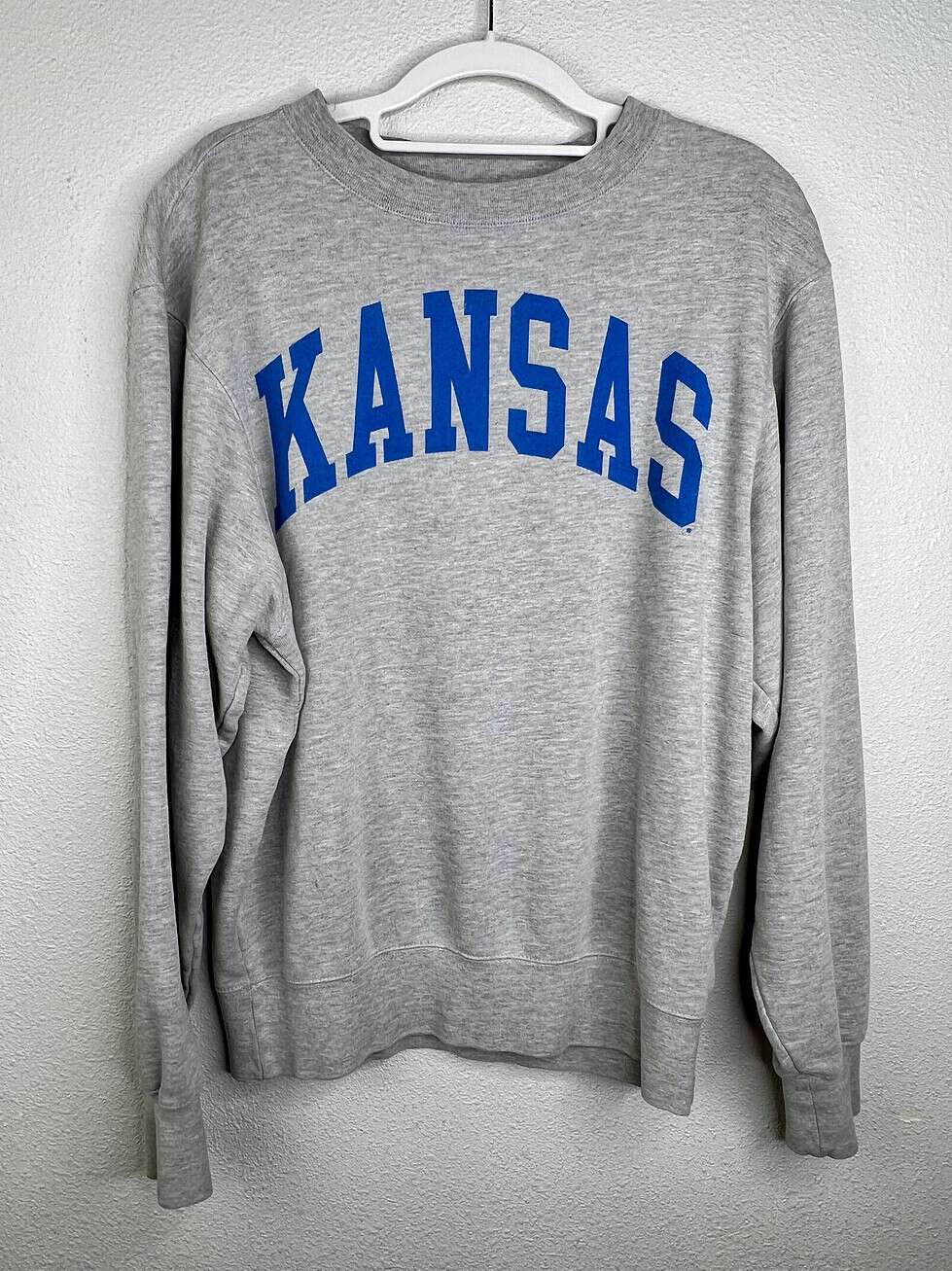 Front view of gray Kansas crewneck sweatshirt featuring blue collegiate-style lettering.