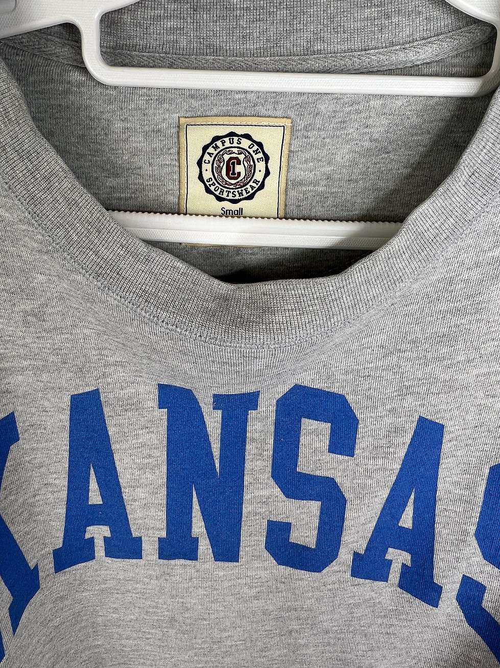 Close-up of Campus One Sportswear tag and bold blue "KANSAS" lettering on the front.