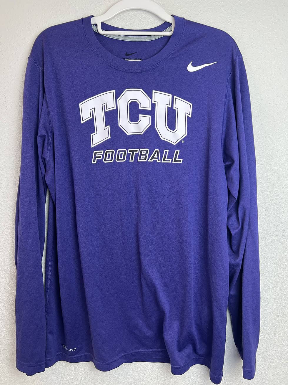 Purple TCU Nike Dri-FIT long-sleeve tee with "TCU Football" text in white, crewneck design, size medium.