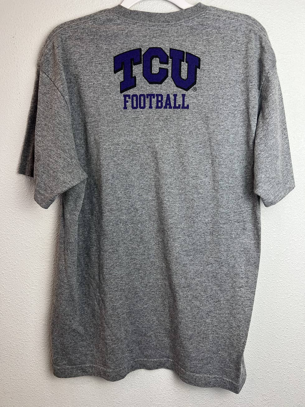 Gray Nike TCU football shirt with purple football graphic “TCU Football” text on back