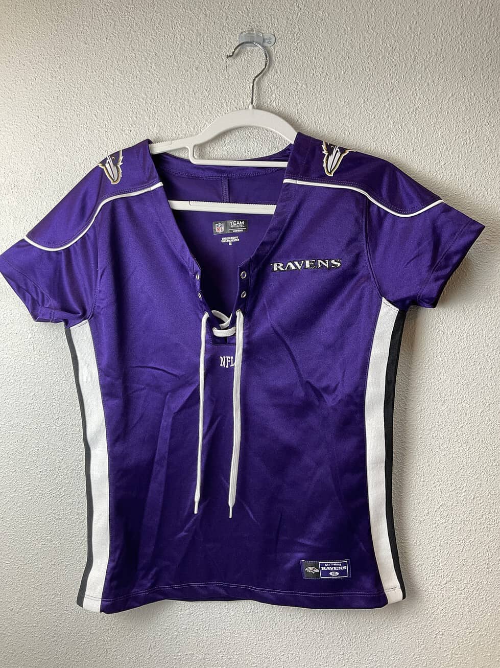 Purple Baltimore Ravens women’s lace-up jersey tee with black and white side panels, embroidered logo on chest and shoulders, size medium.