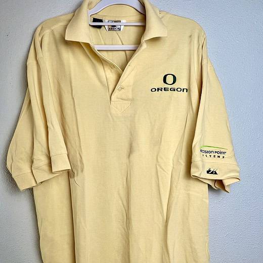 Front view of pale yellow Cutter & Buck polo with Oregon Ducks logo.