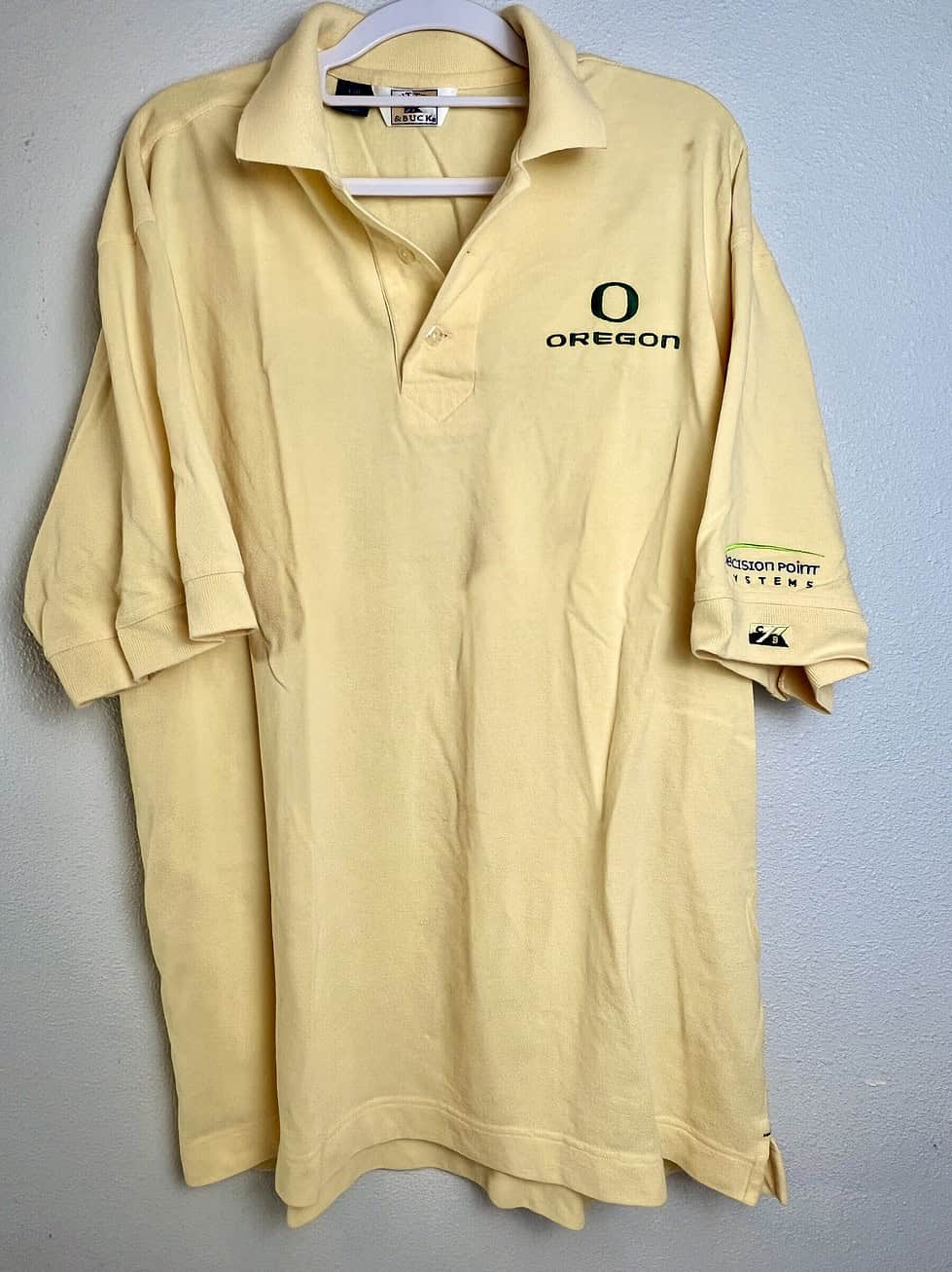 Front view of pale yellow Cutter & Buck polo with Oregon Ducks logo.