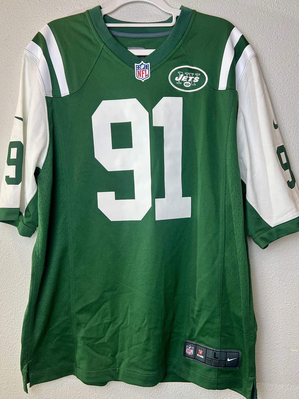 Front of NY Jets #91 jersey, green with white accents and NFL patch.
