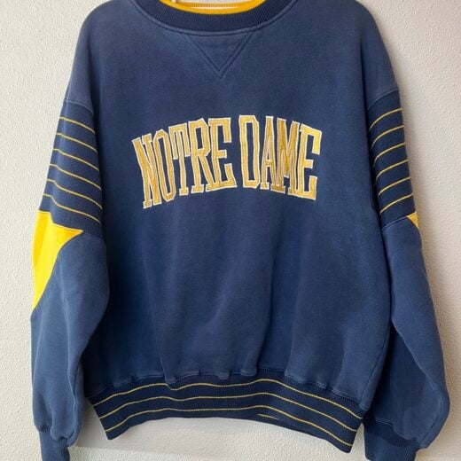 Front of vintage Notre Dame Starter sweatshirt, navy blue with yellow varsity stripes and embroidered lettering.