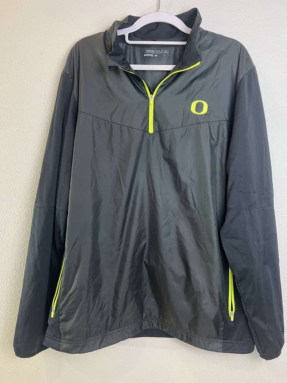 Front view of Nike Golf Oregon Ducks quarter-zip jacket in charcoal gray with Volt yellow accents.