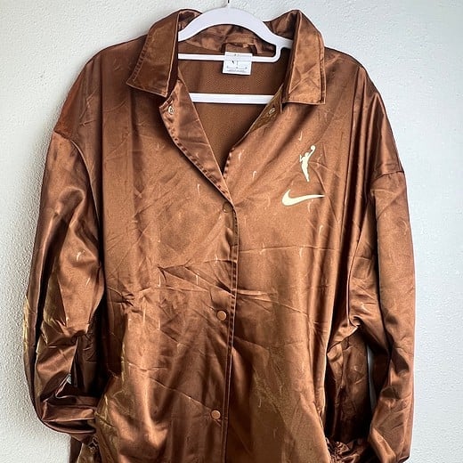 Front view of medium-sized Nike WNBA bronze jacket with Swoosh logo.