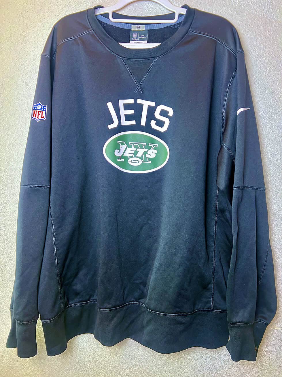 Front of dark gray Nike Jets Therma-FIT sweatshirt with Jets logo and NFL patch.