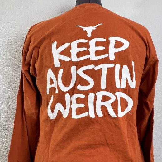 Texas Longhorns burnt orange long-sleeve shirt featuring 'Keep Austin Weird' text.