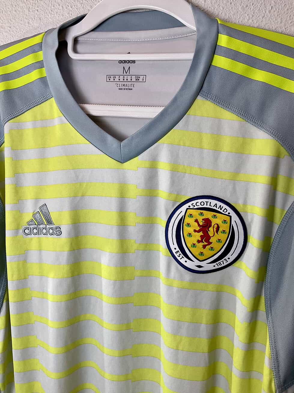 Close-up of Scotland crest and Adidas logo on neon yellow and gray striped design.