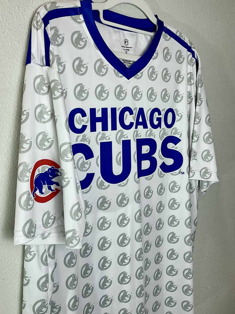 Detailed look at the “CHICAGO CUBS” lettering and Cubs bear head watermark pattern. Blue V-neck trim and sleeve patch add authentic team style.