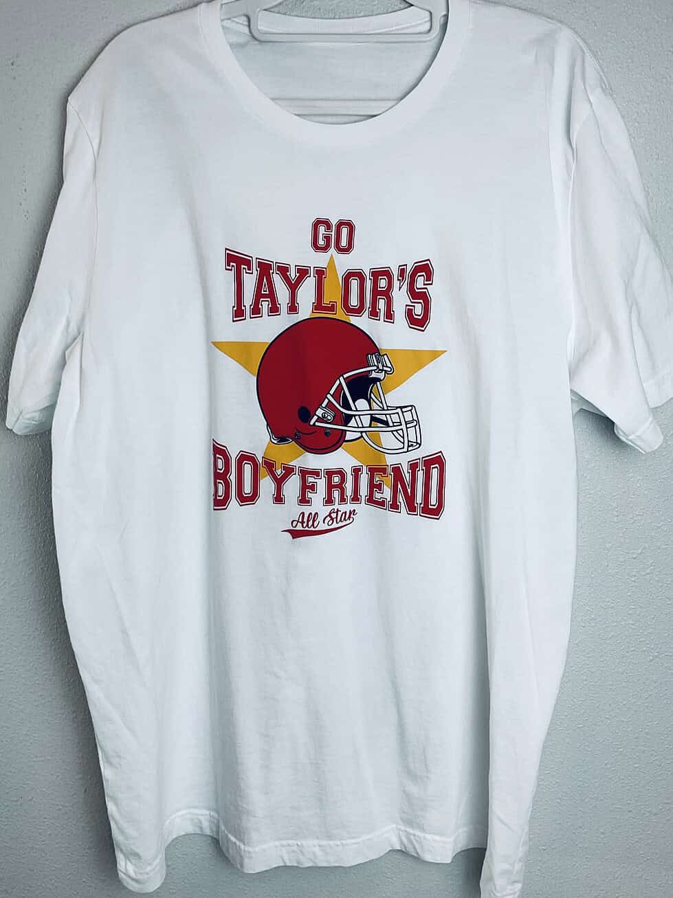 Full view of “Go Taylor’s Boyfriend” Kansas City Chiefs fan T-shirt with red and gold football design.