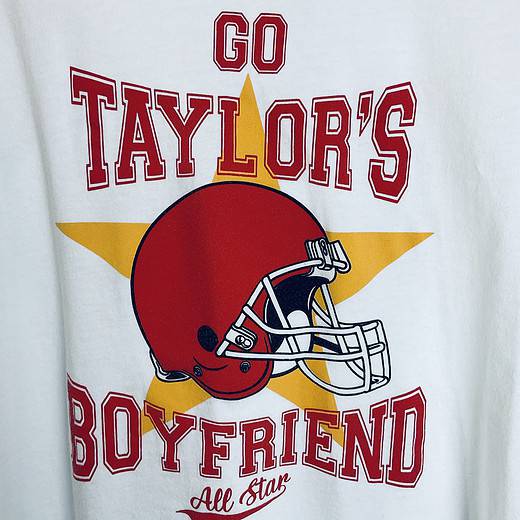 Close-up of text reading “Go Taylor’s boyfriend” and red football helmet graphic on the shirt.