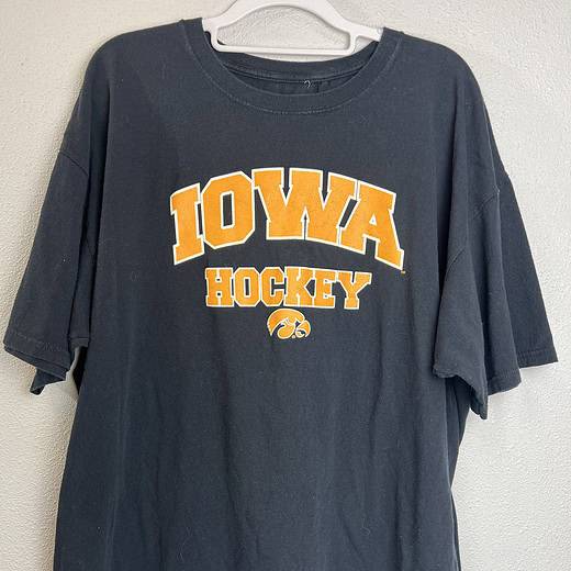 Black Iowa Hawkeyes hockey T-shirt with gold “IOWA HOCKEY” lettering and Hawkeye logo.