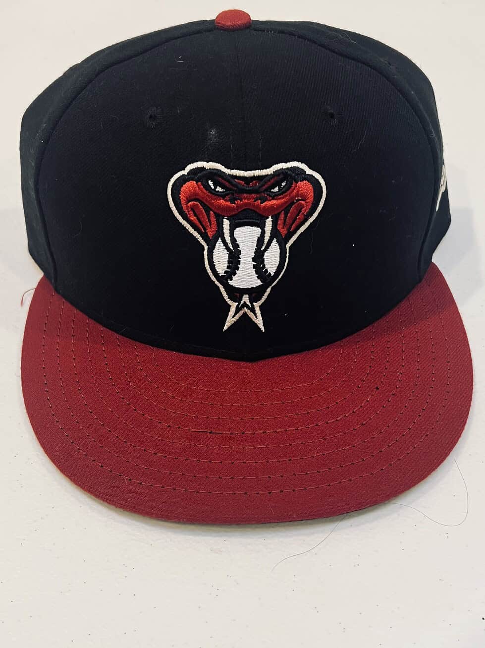 Arizona Diamondbacks fitted hat with black crown and red brim, featuring the snakehead alternate logo with a baseball tongue.