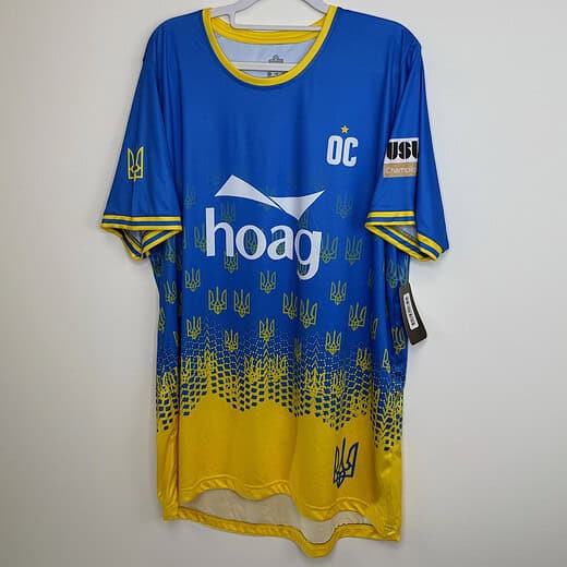 Front view of 2022 Orange County SC jersey in blue and yellow, featuring Ukrainian trident pattern and "OC" championship badge