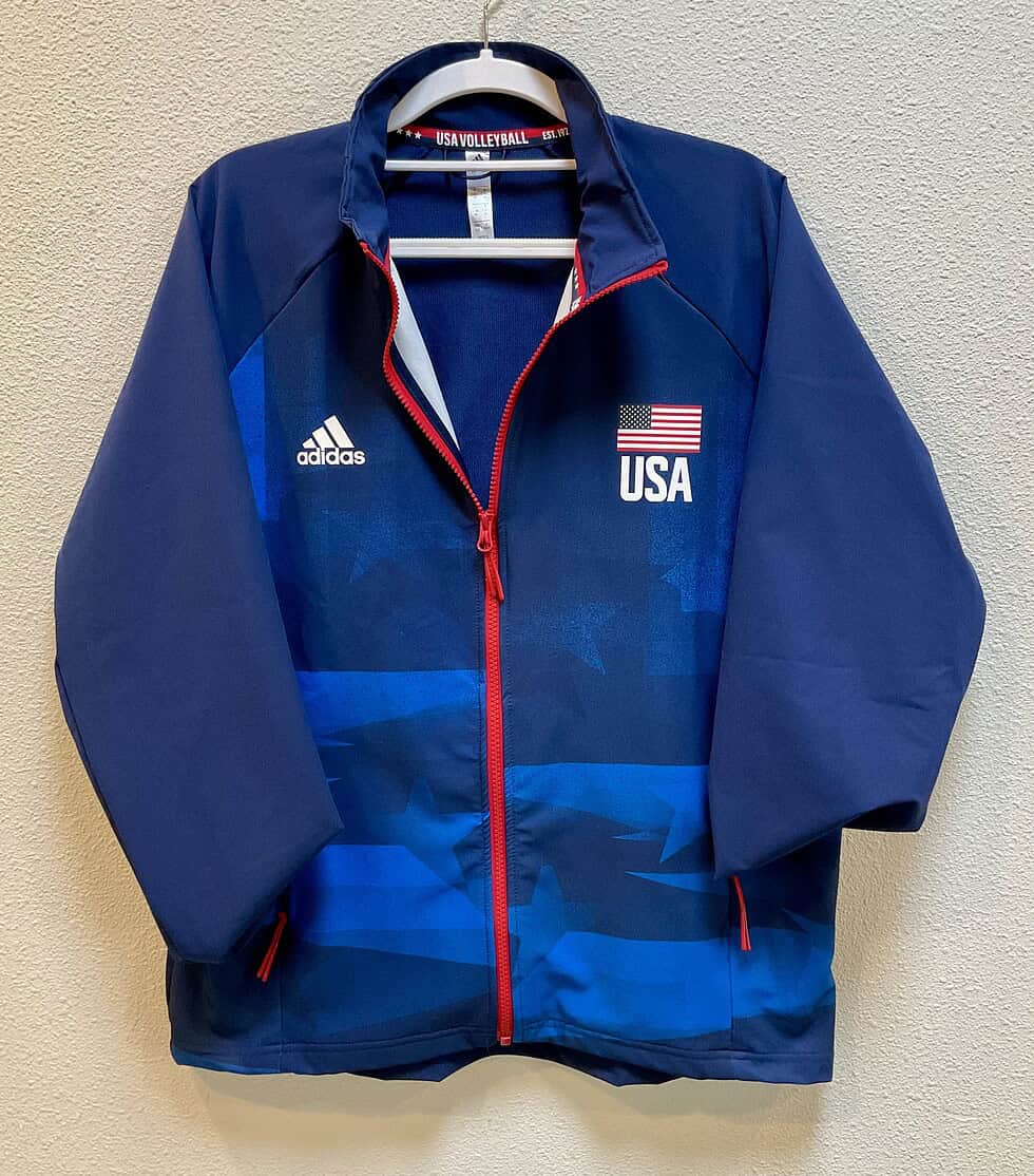 Front view of navy Adidas USA Volleyball jacket with red zipper and USA flag print.