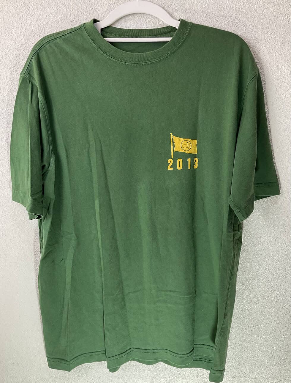 Front view of green 2013 Masters tee with small yellow chest logo and minimal branding