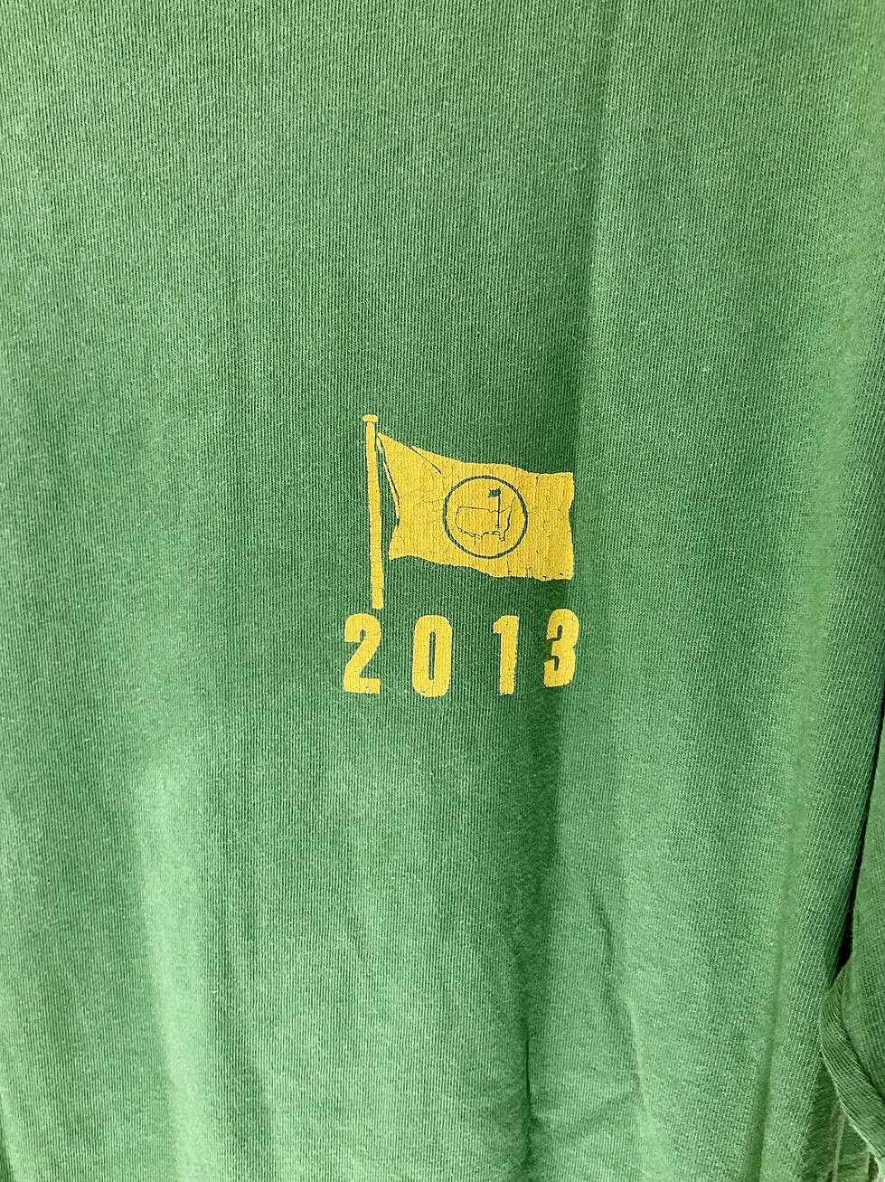 Close-up of cracked yellow flag logo on front of 2013 Augusta National shirt