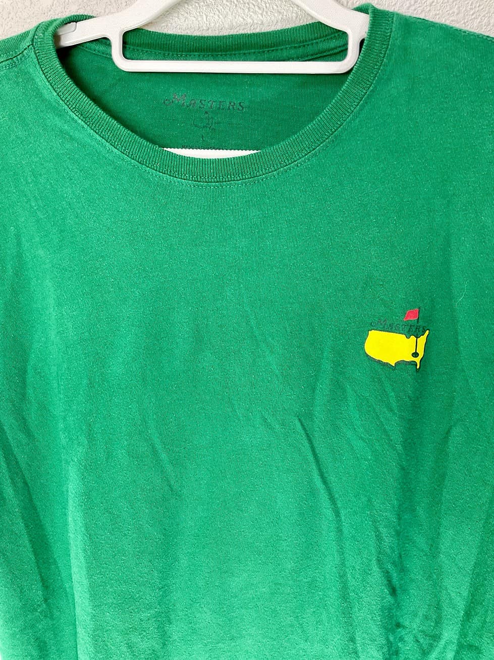 Close-up of chest logo featuring yellow U.S. silhouette and red flag on 2016 Masters tee