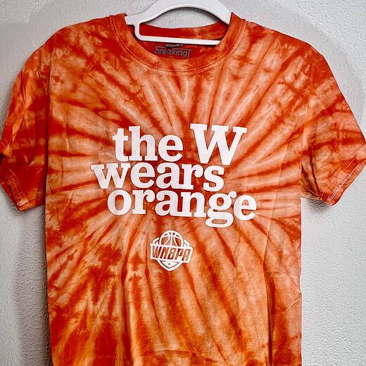 Orange tie-dye BreakingT WNBPA shirt with “The W Wears Orange” graphic