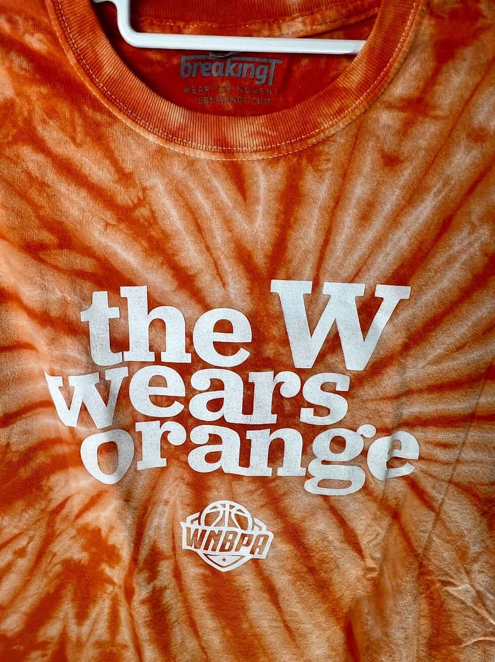 Close-up of WNBPA logo and slogan on orange tie-dye t-shirt