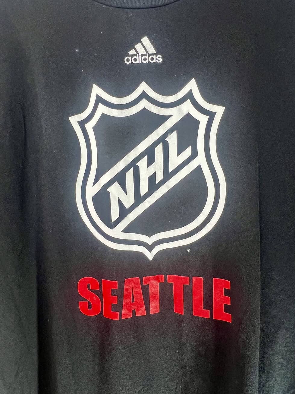 Close-up of NHL logo and Seattle text on Adidas tee from pre-Kraken era