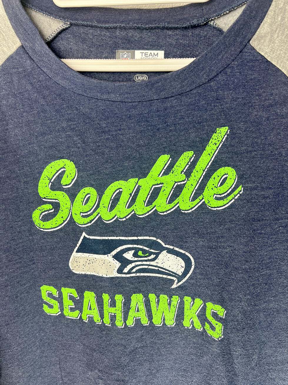 Close-up of Seahawks script logo and team emblem on soft crewneck