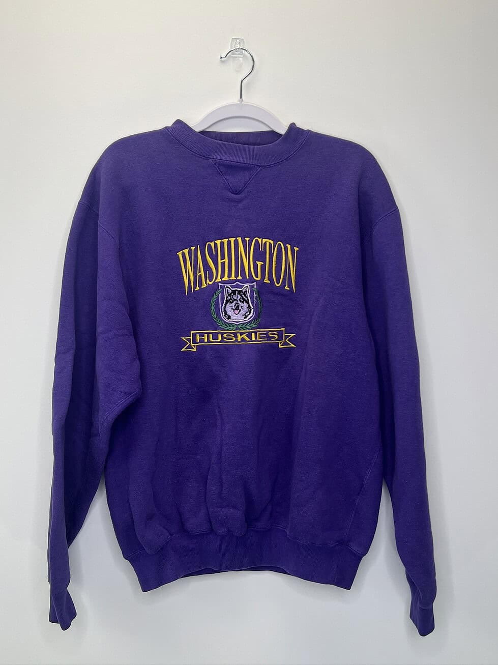 Front view of a vintage purple Washington Huskies Logo 7 crewneck sweatshirt with embroidered Husky graphic and text.