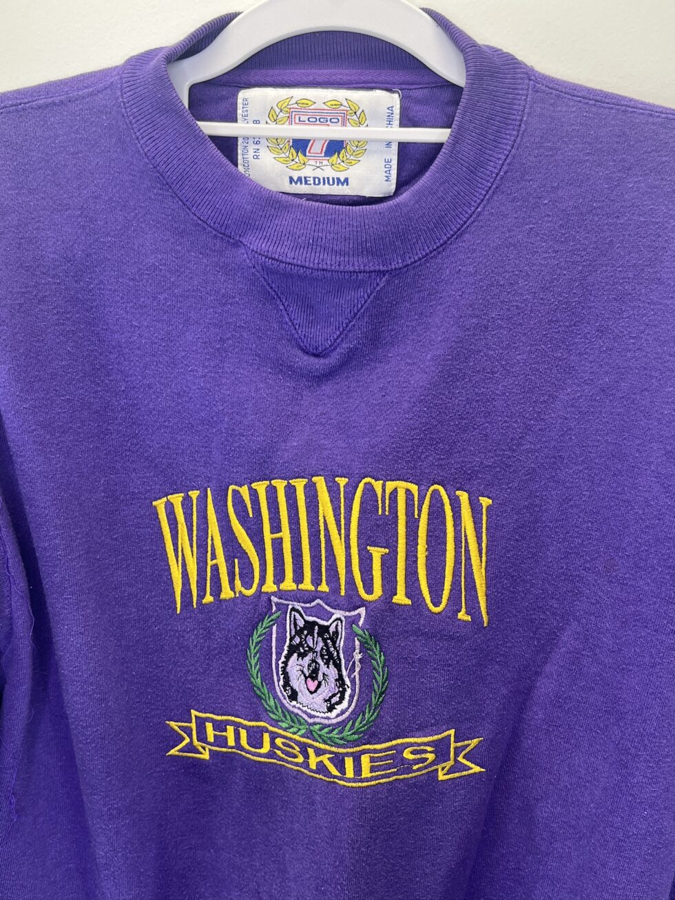 Front view of a vintage purple Washington Huskies Logo 7 crewneck sweatshirt with embroidered Husky graphic and text.