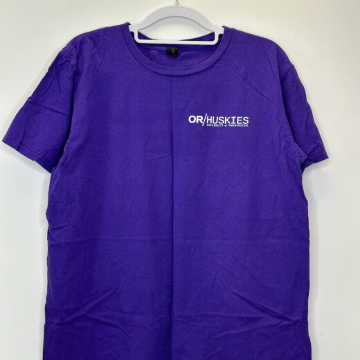 Front and back views of a purple University of Washington "OR/Huskies" t-shirt from the 2018 University Cup in Portland, featuring a dragon boat graphic and collegiate branding.