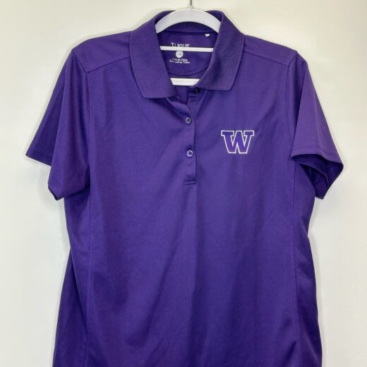 Front of a purple University of Washington women’s polo by Clique, featuring embroidered “W” logo and classic collar.