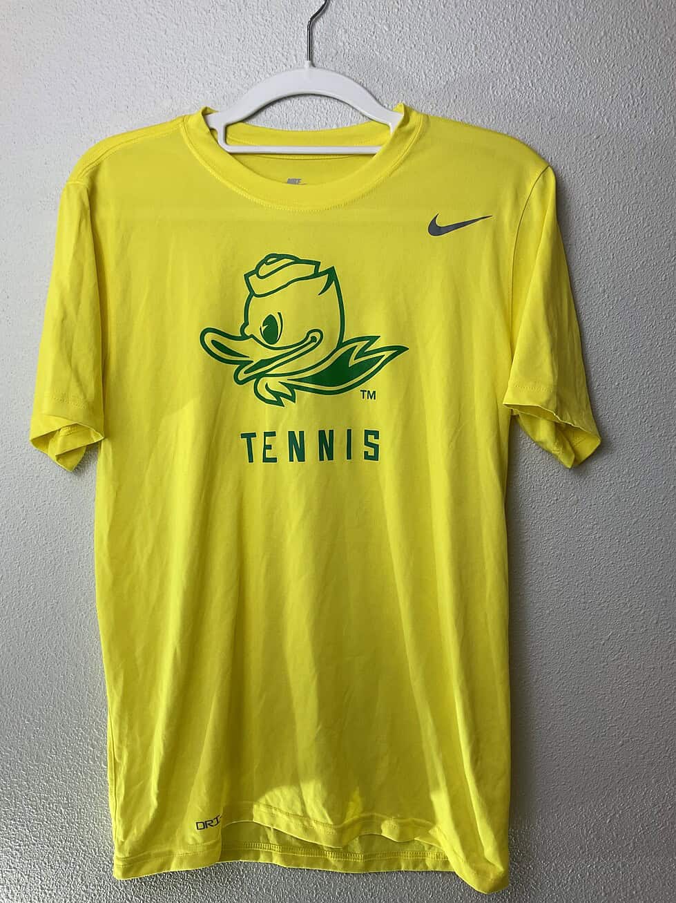 Close-up of University of Oregon Ducks Tennis Nike Dri-FIT tee showing green duck mascot and “TENNIS” print