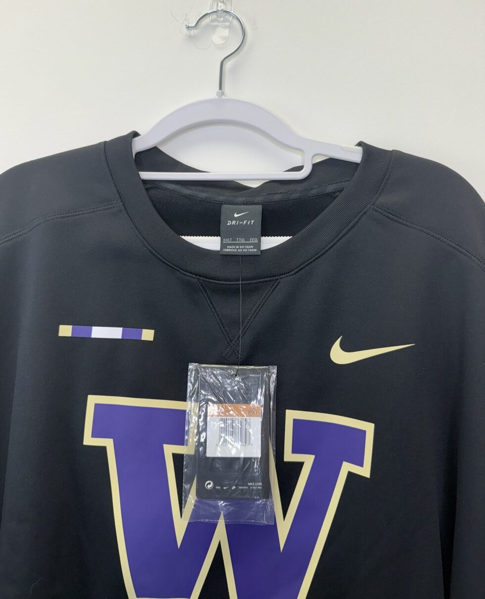 Front of a black Washington Huskies Nike Dri-FIT sweatshirt with gold swoosh and official on-field tag, size 2XLT.