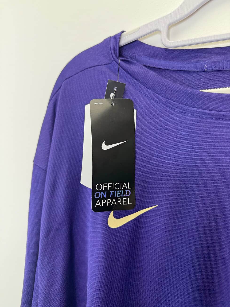 Front of a purple Nike Dri-FIT long-sleeve shirt and official on-field apparel tags.
