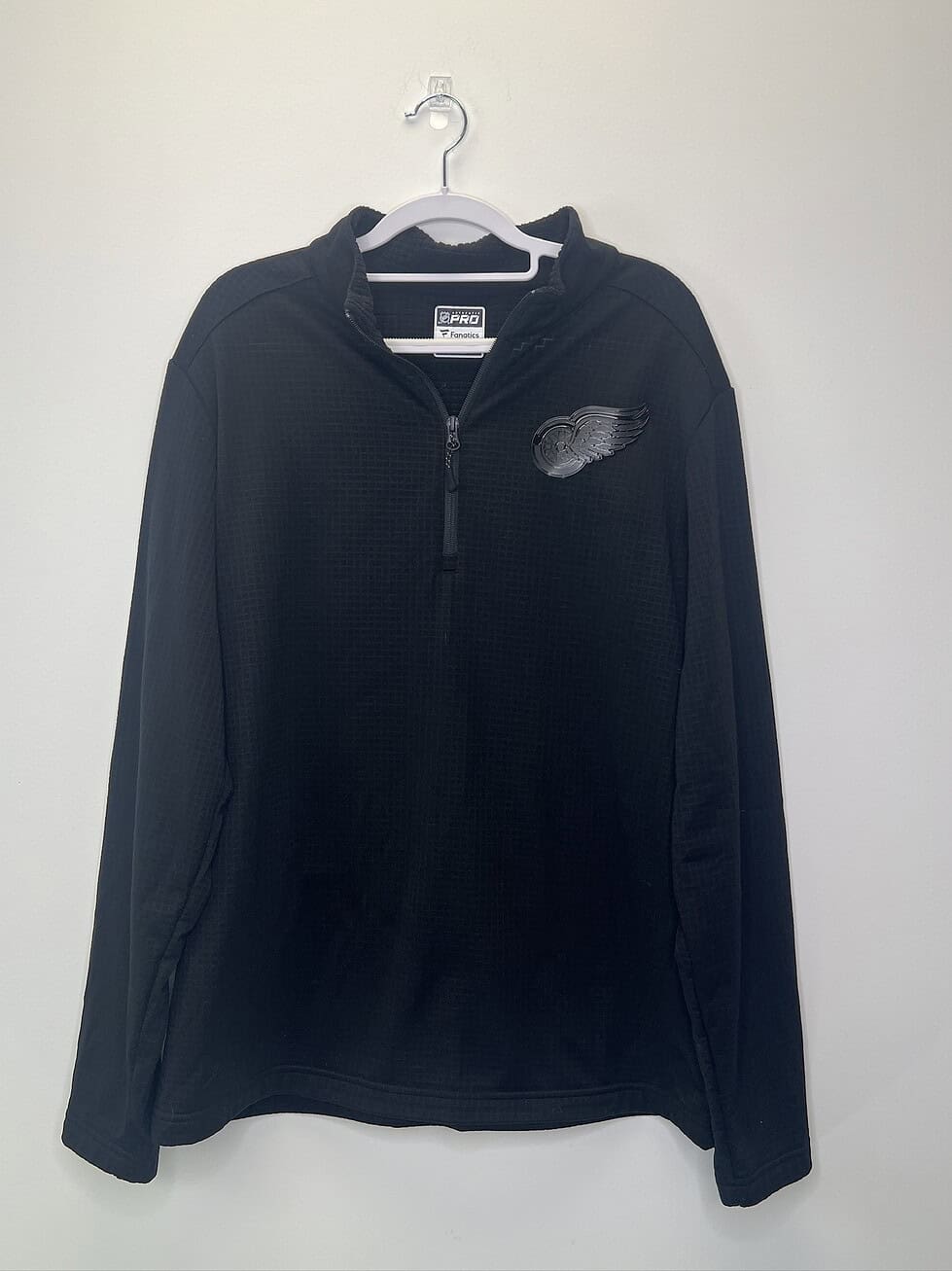 Front, close-up, and back views of a black NHL Fanatics Pro quarter-zip pullover with tonal Detroit Red Wings logo and waffle knit texture.