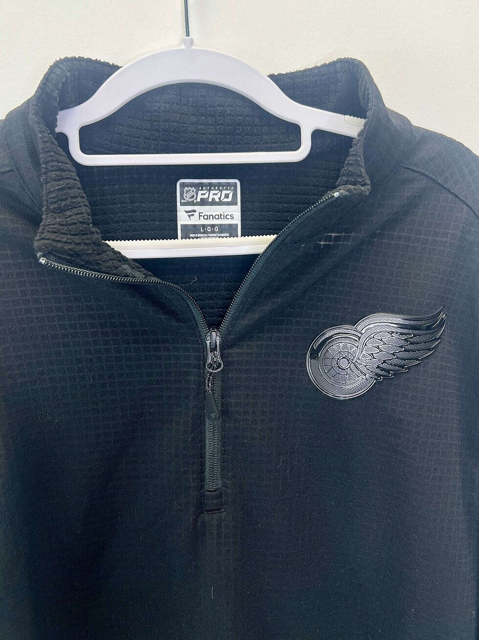 Front, close-up, and back views of a black NHL Fanatics Pro quarter-zip pullover with tonal Detroit Red Wings logo and waffle knit texture.