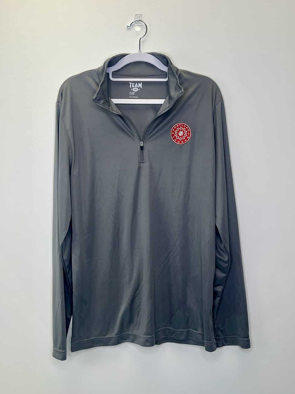 Gray long-sleeve quarter-zip pullover with Portland Thorns FC crest on left chest, displayed on hanger against white background.